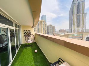 uma varanda com relva verde e uma bola de futebol no chão em Luxury two bedroom شقة فخمة وكبيرة غرفتين em Ajman