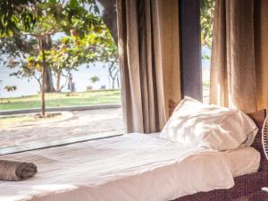 a bed sitting in front of a window at Thumbi View Lodge in Cape Maclear