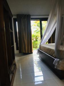 a bedroom with a bed and a window in a room at Puring Bungalows in Gili Air