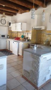a large kitchen with white cabinets and a counter top at Maison de bourg in Saint-Maurice-les-Brousses