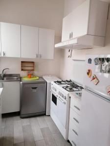 uma cozinha com armários brancos e um forno com placa de fogão em Valerie Apartment em Gallipoli