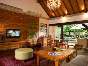 een woonkamer met een tafel en een televisie bij Bintang Bali Villa in Kuta