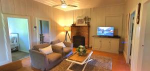 a living room with two chairs and a television at Old Schoolmaster's Cottage on the Barrington River in Barrington