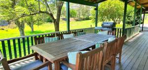 a wooden table and chairs on a deck with a grill at Old Schoolmaster's Cottage on the Barrington River in Barrington
