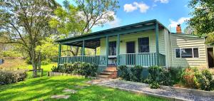 a green and white house with a yard at Old Schoolmaster's Cottage on the Barrington River in Barrington