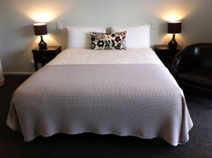 um quarto com uma grande cama branca e 2 candeeiros em Darfield Motel em Darfield