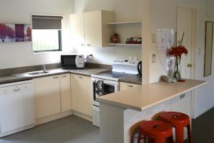 una cocina con armarios blancos y una barra con taburetes rojos en Darfield Motel, en Darfield