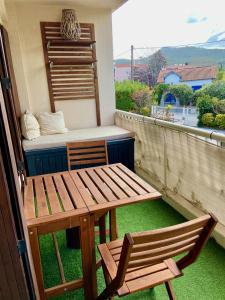 uma mesa e cadeira de madeira numa varanda com uma cama em La Frégate - appartement à 100 m de la plage em Saint-Cyr-sur-Mer