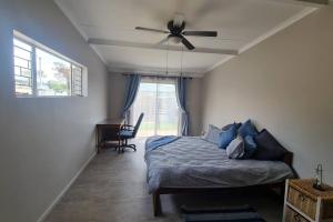 a bedroom with a bed and a ceiling fan at Rock away Beach Condo. in Hartenbos