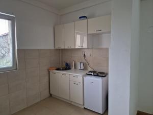 a small kitchen with white cabinets and a sink at Apartman Tološi in Podgorica