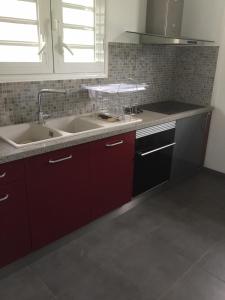 eine Küche mit roten Schränken und einem Waschbecken in der Unterkunft Bas de villa cosy in Le Lamentin