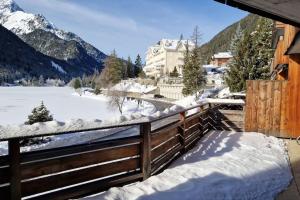 einen schneebedeckten Balkon mit einem Zaun und verschneiten Bergen in der Unterkunft Superbe appartement Champex-Lac avec piscine et sauna in Champex