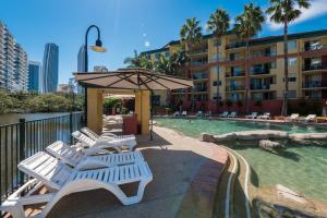 a group of white lounge chairs next to a swimming pool at Paradise Island Resort in Gold Coast