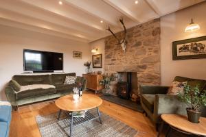 - un salon avec des canapés et un mur en pierre dans l'établissement Trevidgeowe Farmhouse, à Bodmin