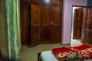 Schlafzimmer mit Holzschränken und einem Bett mit einer roten Decke in der Unterkunft Plan B Complex in Buea
