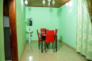 Buea的住宿－Plan B Complex，一间带桌子和红色椅子的用餐室