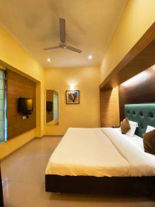 a bedroom with a large bed and a tv at Status Business Hotel - Naveen Market in Kānpur