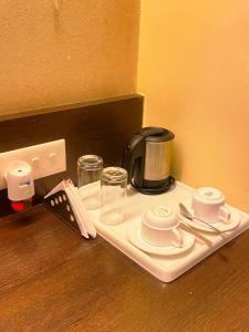 a tray with a coffee maker and cups on a table at status business hotel in Kānpur