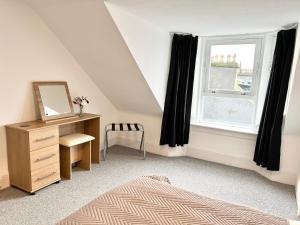 a bedroom with a bed and a dresser and a window at Douglas Street Apartment in Nairn
