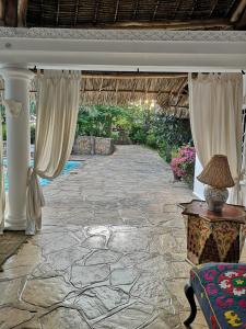 eine Steinterrasse mit Vorhängen und einem Tisch in der Unterkunft Fulvia House in Malindi