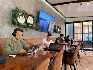 un grupo de personas sentadas en mesas con sus ordenadores portátiles en The Venue Hostel Boutique en Valencia