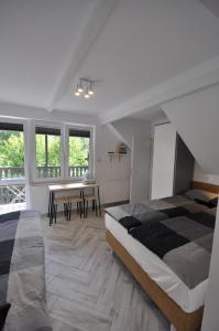 a bedroom with two beds and a table and windows at Dziupla Dębki in Dębki