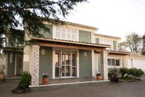 une maison avec une terrasse couverte à l'avant avec des plantes en pot dans l'établissement The Green House Villa (with private pool) Corfu, à Sidari