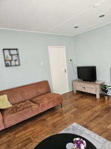 een woonkamer met een bank en een flatscreen-tv bij Vakantiehuis in Oosterwolde