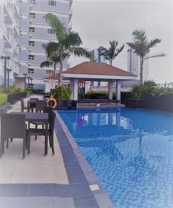 a swimming pool with a table and chairs next to a building at SMDC COAST RESIDENCES in Manila