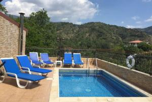 a swimming pool with blue lounge chairs next to it at The Love Holiday House in Tris Elies