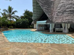 a swimming pool next to a resort with a thatch roof at Fulvia House in Malindi