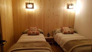 two beds in a room with wooden walls at CASA DONDELA in Roní