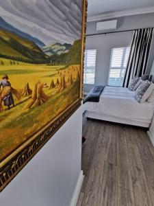 ein Schlafzimmer mit einem Gemälde an der Wand neben einem Bett in der Unterkunft Huis van Brood Guesthouse in Malmesbury