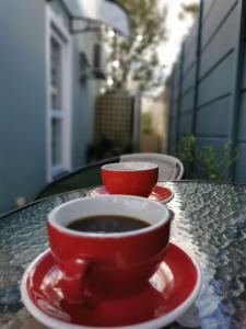 eine rote Tasse Kaffee auf einem Tisch in der Unterkunft Huis van Brood Guesthouse in Malmesbury