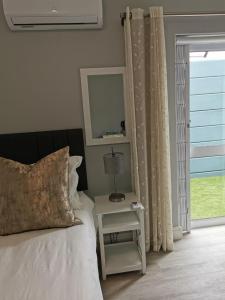 ein Schlafzimmer mit einem Bett und einem Tisch mit einer Lampe in der Unterkunft Huis van Brood Guesthouse in Malmesbury