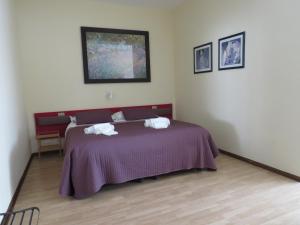 阿普里利亞的住宿－Hotel San Michele，一间卧室配有一张紫色床和两条毛巾