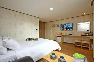 a bedroom with a white bed and a flat screen tv at Traum Hotel & Condo in Gapyeong
