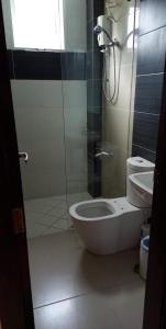 a bathroom with a toilet and a glass shower at GLC SUITES in Bislig