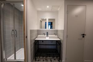 uma casa de banho com 2 lavatórios e um chuveiro em Beau M Paris em Paris