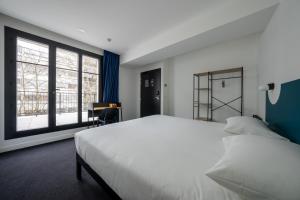 a bedroom with a large white bed and large windows at Beau M Paris in Paris