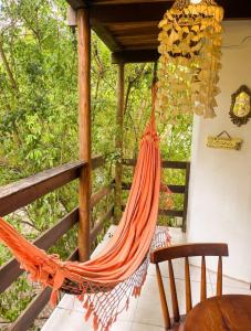 an orange hammock on a porch with a table and chairs at Casa no coração de Praia do Forte in Praia do Forte
