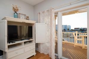 a living room with a tv and a balcony at Salty Girl in Oak Island