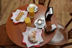 een houten tafel met eten en twee glazen sinaasappelsap bij B&B LE DUE ISOLE in Nuoro