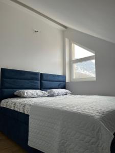 a bedroom with a bed with a blue headboard and a window at Loft apart Pluzine in Plužine