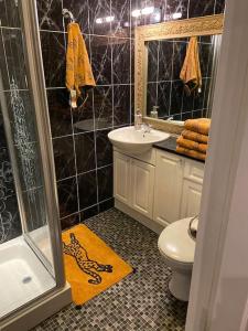 uma casa de banho com azulejos pretos, um WC e um lavatório. em Palm View Luxury Botanical Themed apartment with sauna em St Austell