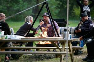 a group of people sitting around a fire at a picnic table at Frya Leir in Frya