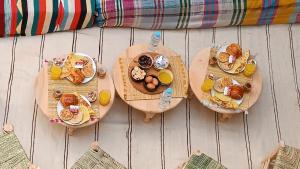 a table with three plates of breakfast foods and orange juice at Happy Marrakchy Hostel in Marrakesh