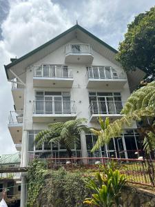 a white building with balconies and palm trees at Misty Paradise of Lake Gregory in Nuwara Eliya