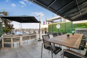 eine Terrasse mit einem Tisch, Stühlen und einem Sonnenschirm in der Unterkunft THE VIADUCT WATERFRONT LUXURY - Views & Location! in Auckland