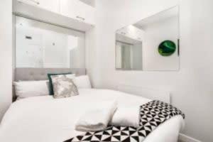 ein weißes Schlafzimmer mit einem Bett und einem Spiegel in der Unterkunft THE VIADUCT WATERFRONT LUXURY - Views & Location! in Auckland